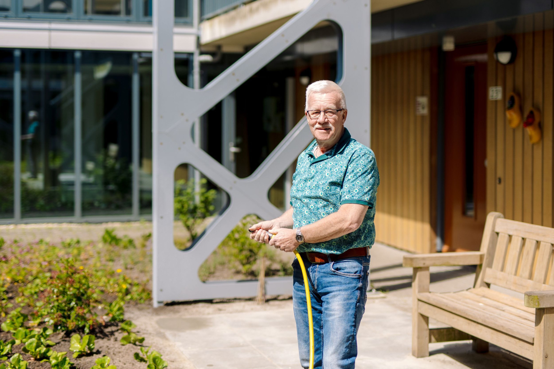Een man sproeit de binnentuin met een tuinslang.